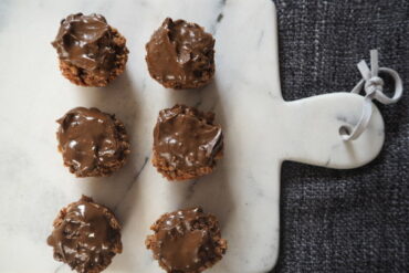 6 chocolate covered small round flapjacks on a marble chopping board