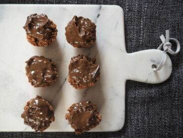 6 chocolate covered small round flapjacks on a marble chopping board