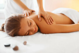 Female lying down with exposed shoulders receiving a massage from a therapiste