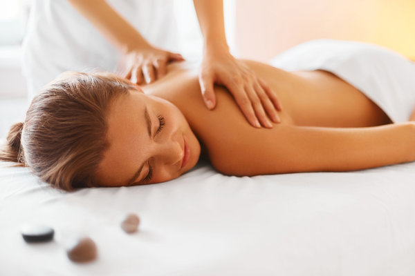 Female lying down with exposed shoulders receiving a massage from a therapiste