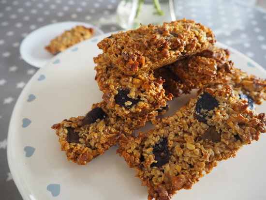 Pile of rectangular flapjacks with figs and walnuts in them sat on a cream cake stand