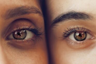 Close up image of two people showing just one of their brown eyes