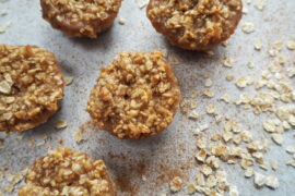Close up of 5 mini round cinnamon flapjacks spinkled with cinnamon and oats on a pale grey background