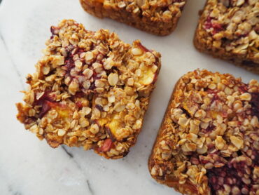 Close up of 4 square peach melba flapjacks on a white marble background
