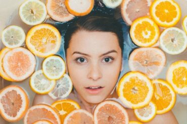 Woman's face submerged in water, surrounded by slices of orange and lemon to indicate she has a healthy eco friendly bathroom