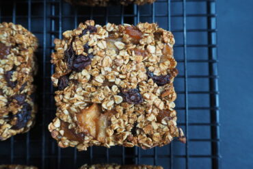Close up of a square apple cinnamon and raisin flapjack on a wire cooling rack