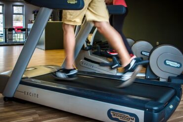 Image of man running on a treadmill fromt eh waist down, focusing on his feet