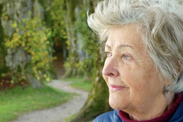 Old lady staring into the distance in outdoor park looking as if she has dementia