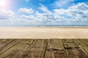Beach - golden sand with sea on the horizon and bright blue sky filed with fluffy clouds