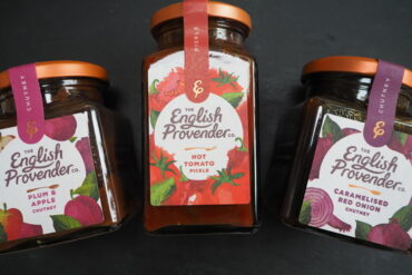 Three jars of The English Provender Co. chutneys and pickle laid down on a dark slate background