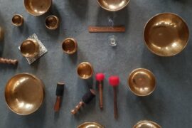 A range of Tibetan singing bowls use for sound therpay and meditation positioned on a grey carpet