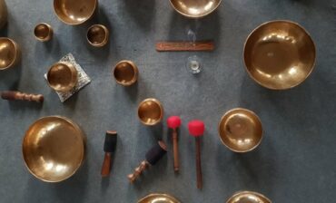 A range of Tibetan singing bowls use for sound therpay and meditation positioned on a grey carpet