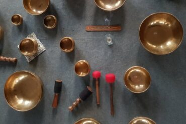 A range of Tibetan singing bowls use for sound therpay and meditation positioned on a grey carpet