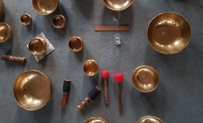 A range of Tibetan singing bowls use for sound therpay and meditation positioned on a grey carpet
