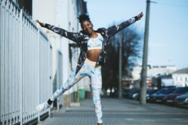 Young black female doing half a star jump, wearing sports gear and happy she's found the right workout plan