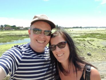 Headshot of male and female wearing sunglasses smiling with beautiful natural harbour in the background. The picture of a healthy happy relationship