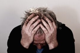 older man holding his head in his hands trying to relieve a headache