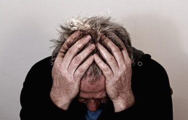 older man holding his head in his hands trying to relieve a headache