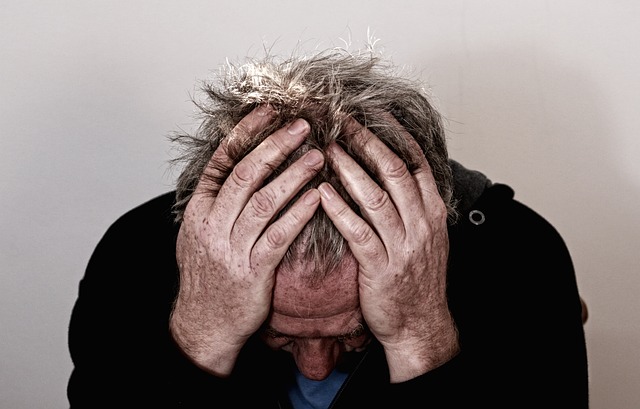 older man holding his head in his hands trying to relieve a headache