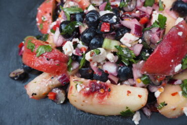 Close up of Chilli, Peach and Blueberry Salad served on a dark grey slate