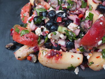 Close up of Chilli, Peach and Blueberry Salad served on a dark grey slate