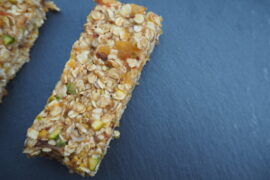 Rectangular no bake vegan date abd aoricot flapjack presented on a dark grey slate board