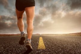 Botoom half of male runner wearing shorts running on a road