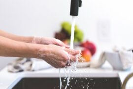 Close up of hands being washed under a running tap in a kitchen to show the importance of good personal hygiene