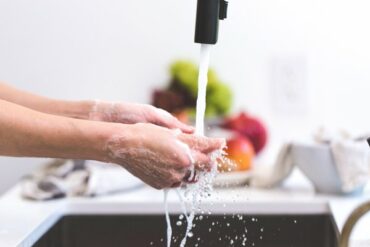 Close up of hands being washed under a running tap in a kitchen to show the importance of good personal hygiene