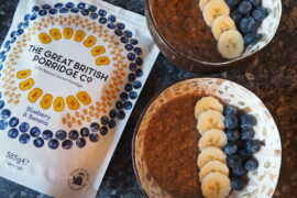 Packet of Blueberry & Banana The Great British Porridge Co. Porridge next to two bowls of porridge topped with sliced banana and blueberries