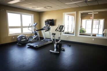 Three exercise machines positioned in the corner of an emoty fitness studio - a treadmill, exercise bike and cross trainer