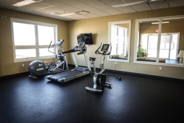 Three exercise machines positioned in the corner of an emoty fitness studio - a treadmill, exercise bike and cross trainer