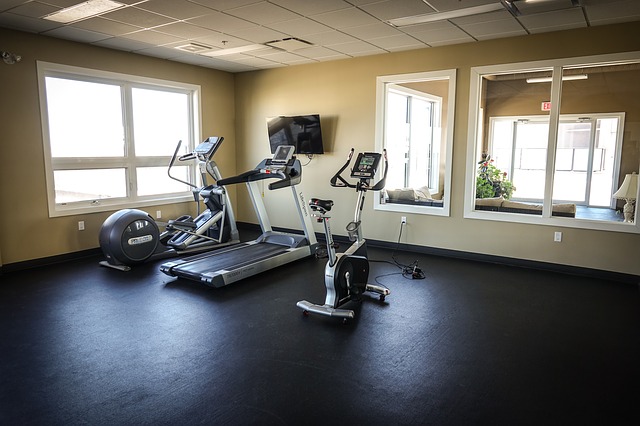 Three exercise machines positioned in the corner of an emoty fitness studio - a treadmill, exercise bike and cross trainer