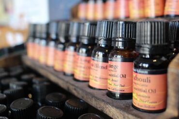 three rows of massage oil bottles lined up on wodden shelves with orange labels
