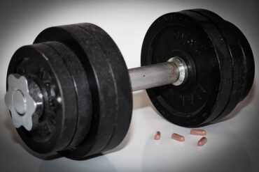 Dumbbells woth 4 capsules of steroid tablets next to them