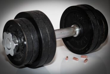 Dumbbells woth 4 capsules of steroid tablets next to them