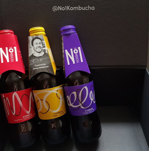Three bottle of No1 Kombucha propped up against a black box