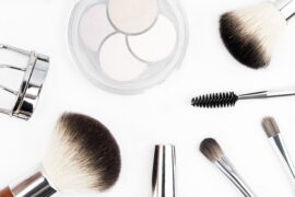 Selection of make up brushes and beauty tools laid out on a bright white background