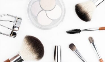 Selection of make up brushes and beauty tools laid out on a bright white background
