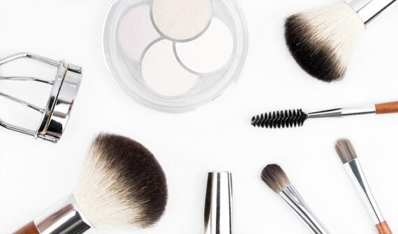Selection of make up brushes and beauty tools laid out on a bright white background
