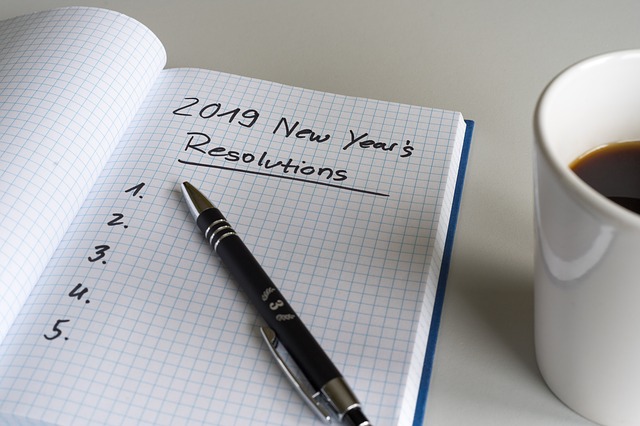 Notebooked opened up with the words 2019 New Year's Resolutions written and underlined on it.
