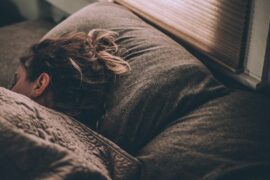 Vergy grey picture of a long haired woman lying in bed trying to depict the winter blues at this time of year.