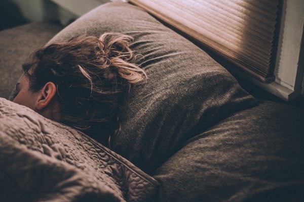 Vergy grey picture of a long haired woman lying in bed trying to depict the winter blues at this time of year.