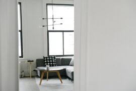 looking through a white doorway into a very modern wiary white living room that looks clean and fresh