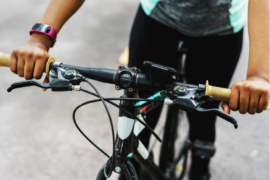 Close up of a bike's handlebars with a person sat on the bike to indicate the health benefits of cycling