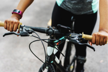 Close up of a bike's handlebars with a person sat on the bike to indicate the health benefits of cycling