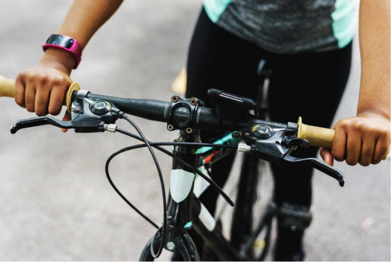 Close up of a bike's handlebars with a person sat on the bike to indicate the health benefits of cycling