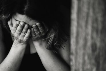 black and white photoe on a woman with her head in her hands grieving