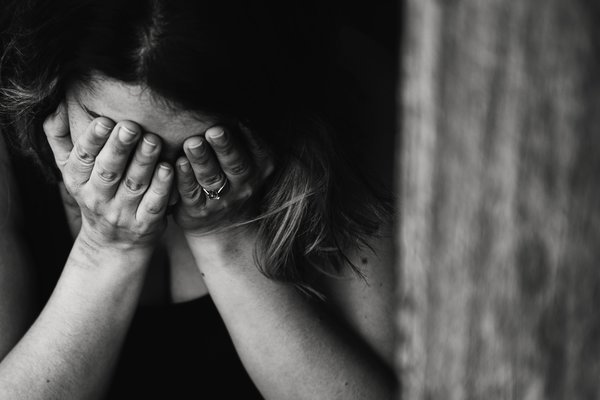 black and white photoe on a woman with her head in her hands grieving