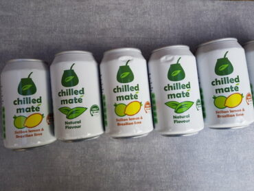 5 cans of Chilled Mate Yerba Energy Drinks laid flat in a diagonal line across a light slate grey background
